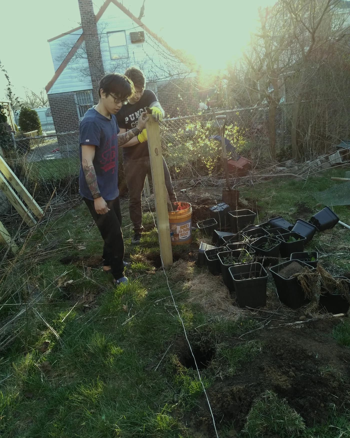 Two people building a greenhouse frame in a yard
